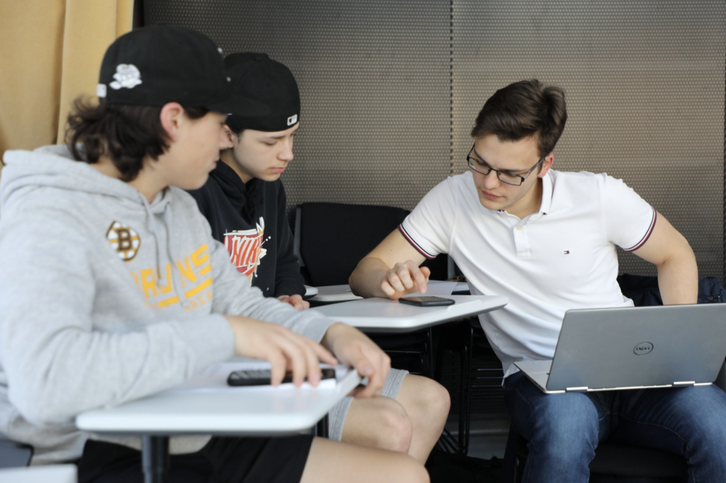 Three students sitting around a desk.