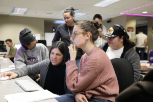 Five people gathered around facing a desk