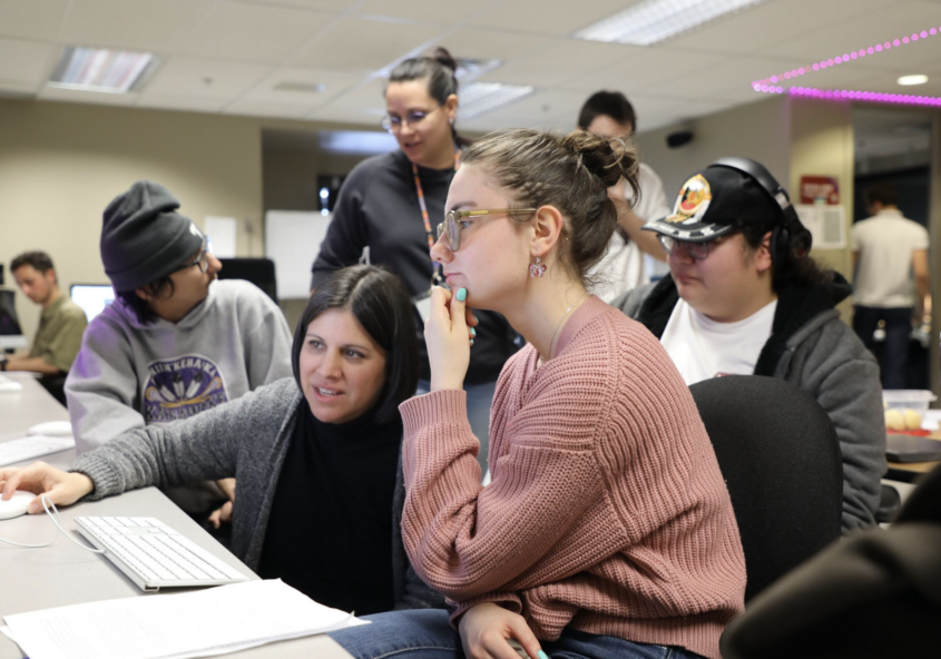 Five people gathered around facing a desk