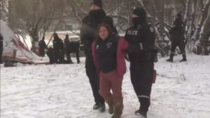 In this image Brandi Morin is being arrested by police officers and being taken away by one on either side