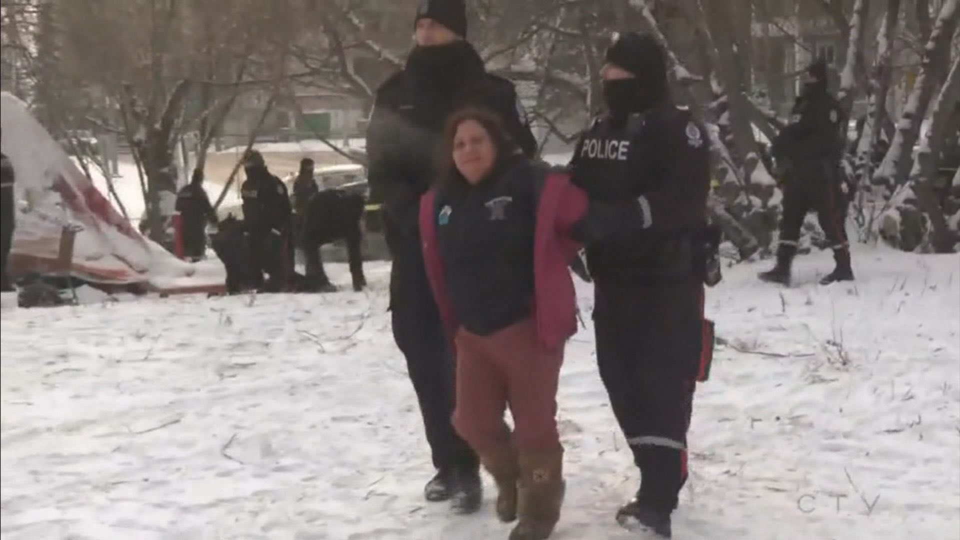 In this image Brandi Morin is being arrested by police officers and being taken away by one on either side