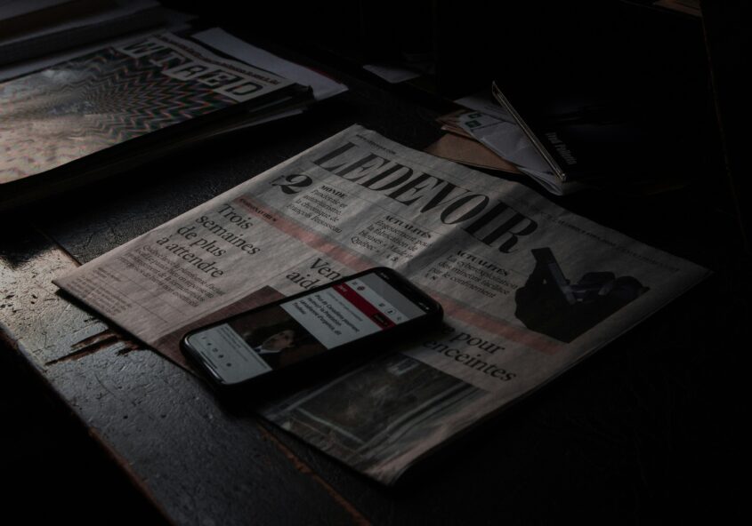 black smartphone on newspaper beside newspaper
