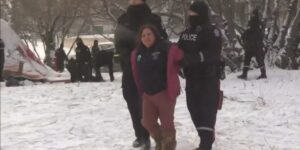 In this image Brandi Morin is being arrested by police officers and being taken away by one on either side